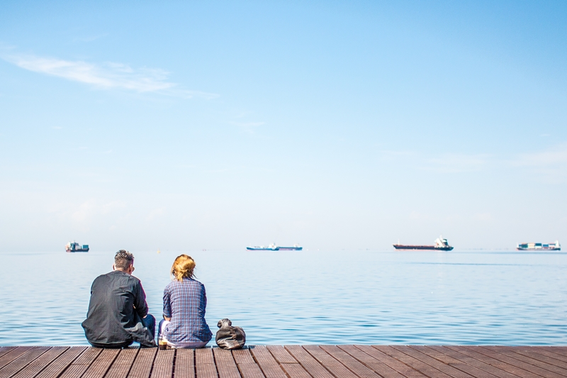Man and woman sitting on a dock looking out over the water.